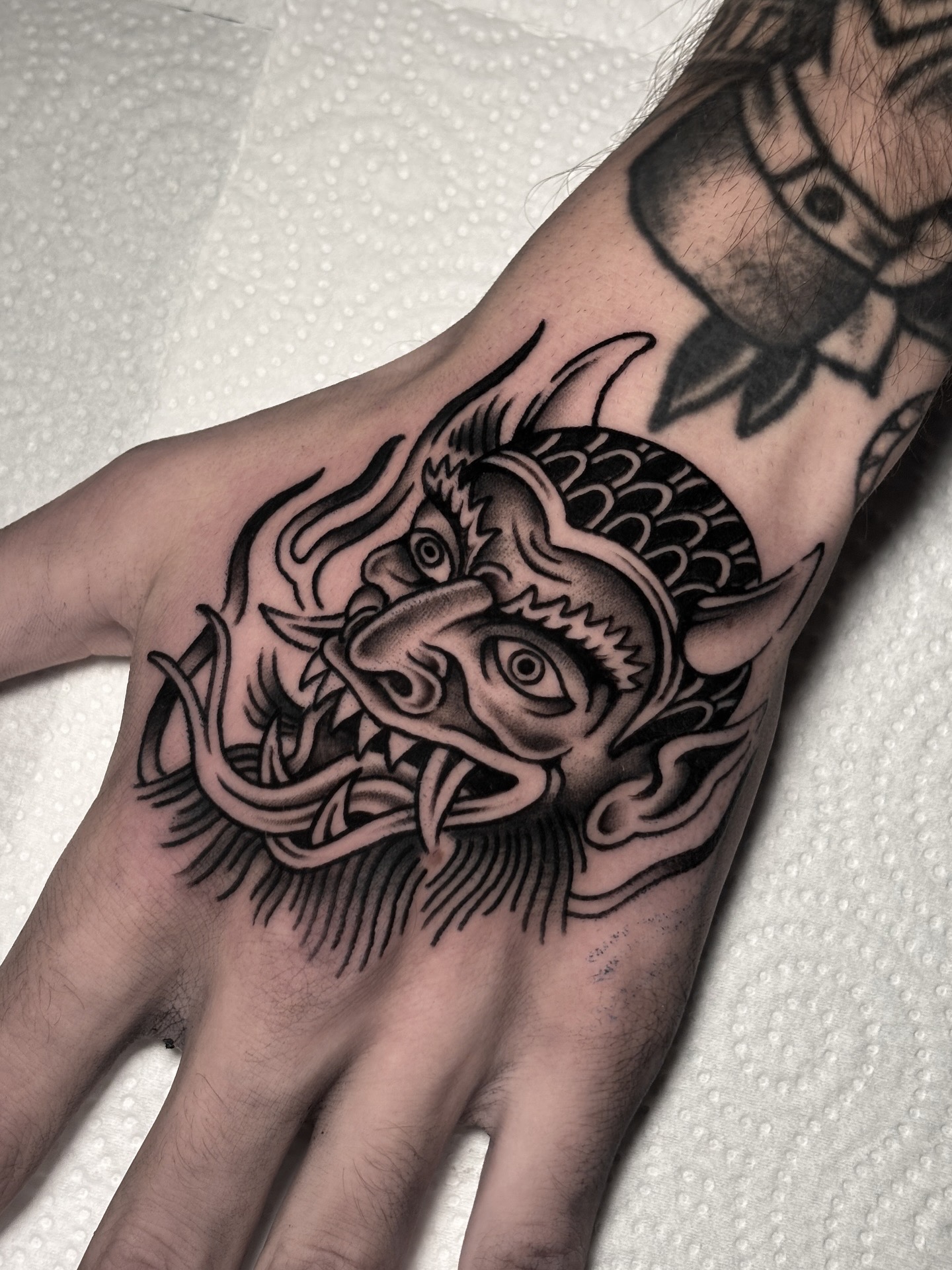 Tatuaje tradicional dragón mano Brego Tattoo Verín Ourense